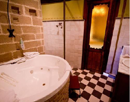 baño de habitacion doble superior con paredes de ladrillo y un jacuzzi redondo blanco en un hotel en Cassalarreina, La Rioja