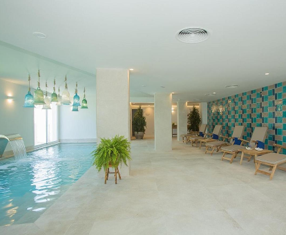 Foto de la piscina cubierta climatizada con cascada de agua y tumbonas