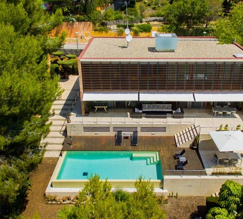 Foto desde el aire de la villa Tamarit Grand Design donde se ve las forma rectas y modernas de la villa con mucha naturaleza alrededor y la piscina frente a la casa